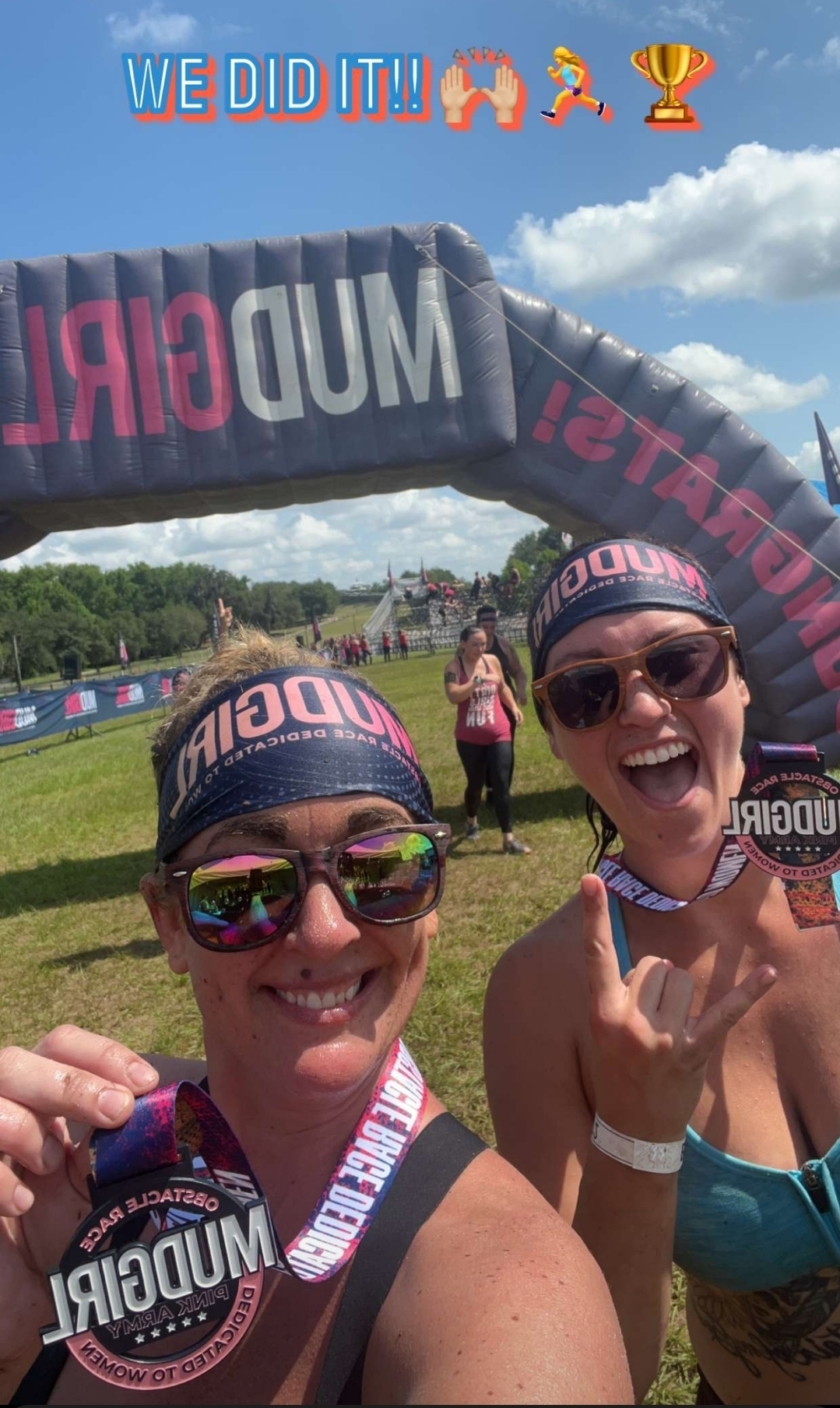 Carissa and Michelle at the Mud Girl finish line, medals and Mud Girl arch behind them